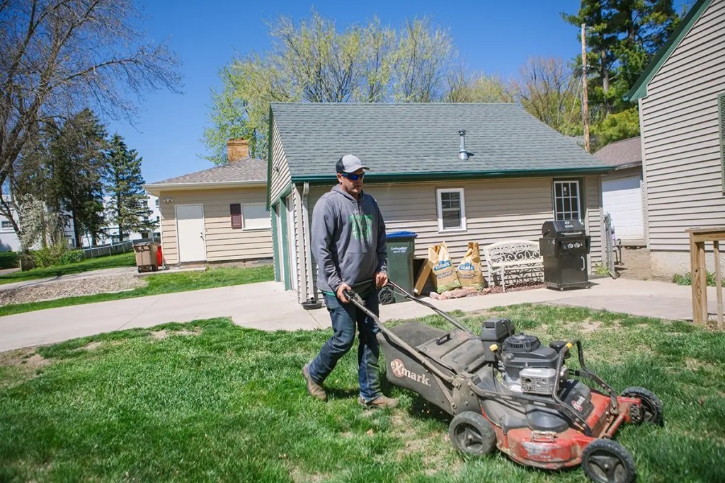Owner of Madison Lawn & Landscape, Nick Bahr, mowing the lawn of a residential property.